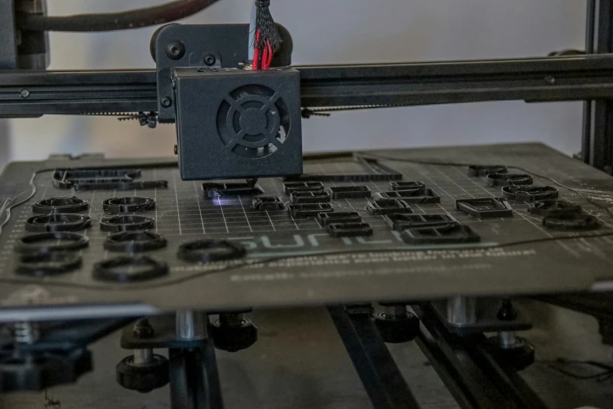 Impressora 3D produzindo vários componentes sobre a mesa, fotografia ilustrativa